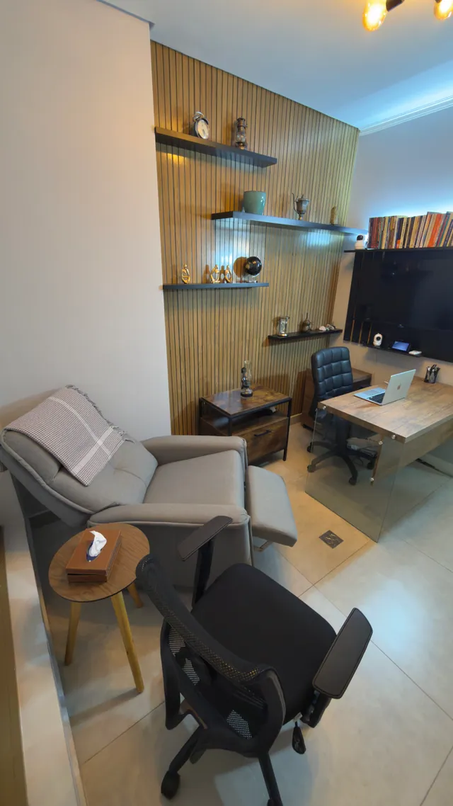 Sala de atendimento de Everson Varoly, com poltrona reclinável, cadeiras e mesa de madeira